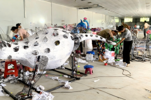 Εργάτες στο εργαστήριο HOYECHI συναρμολογούν και διακοσμούν ένα μεγάλο φανάρι με ζώα κατά παραγγελία, δείχνοντας την πραγματική διαδικασία παραγωγής του φαναριού.