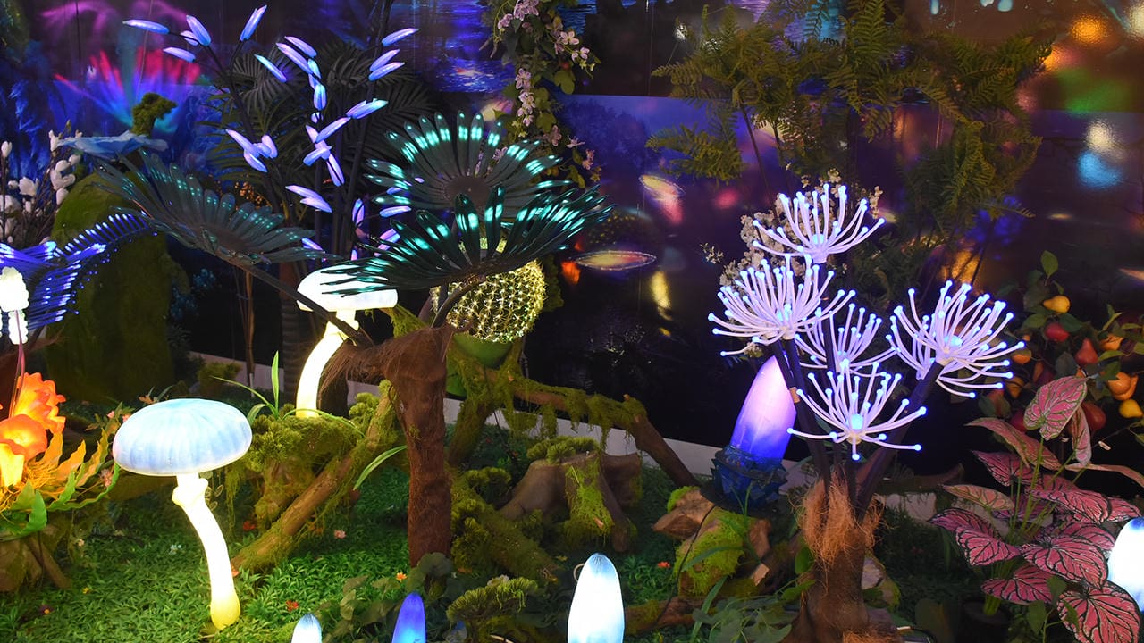 Illuminated fantasy trees and plant forms arranged in a prehistoric-style scene