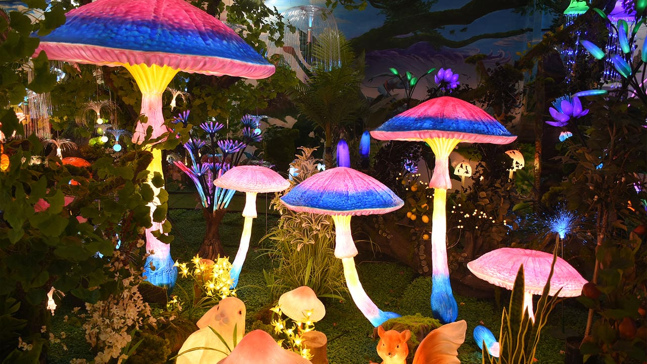 Large illuminated mushroom lanterns surrounded by flowers and plants
