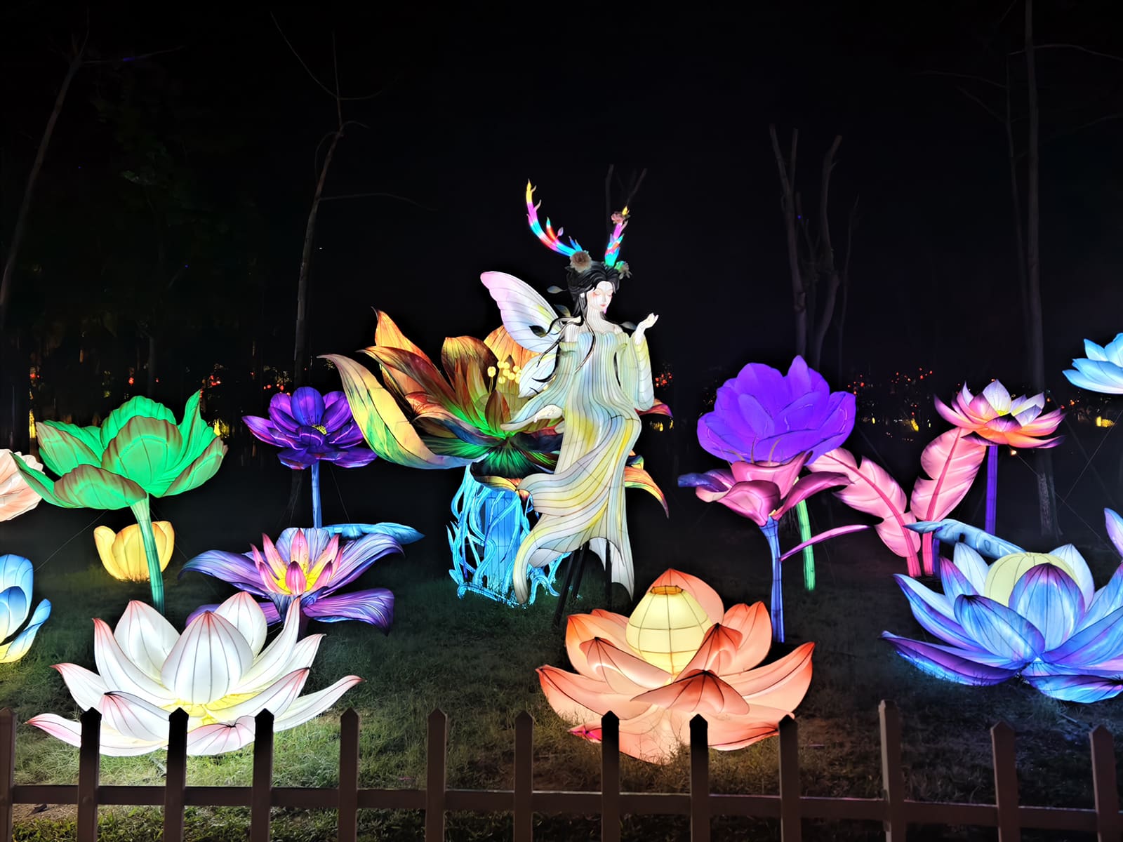 Winged fantasy figure seated among colorful lotus flower lanterns