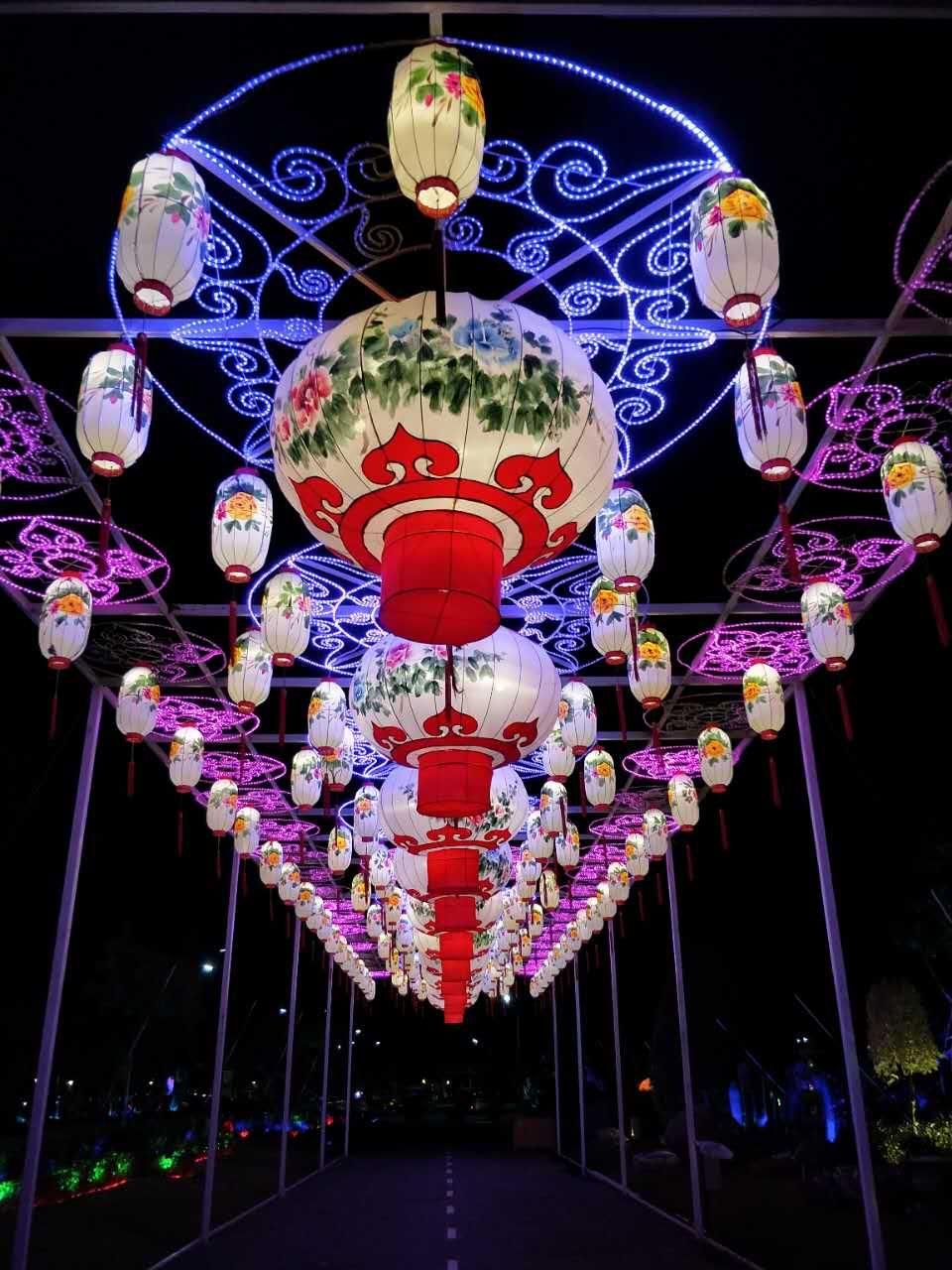 Real illuminated hanging lantern corridor with floral lanterns and decorative light patterns at night