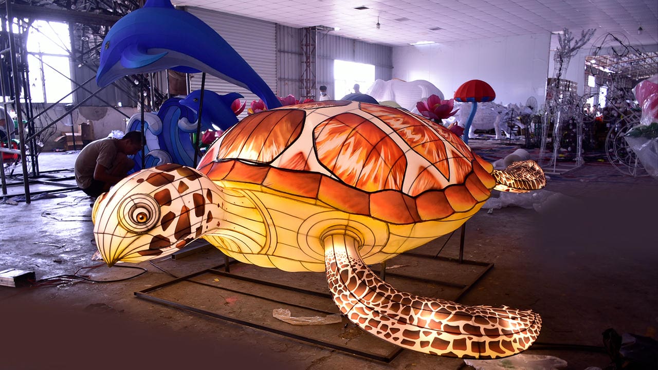 Large illuminated sea-turtle lantern with a blue dolphin and wave lantern in the background