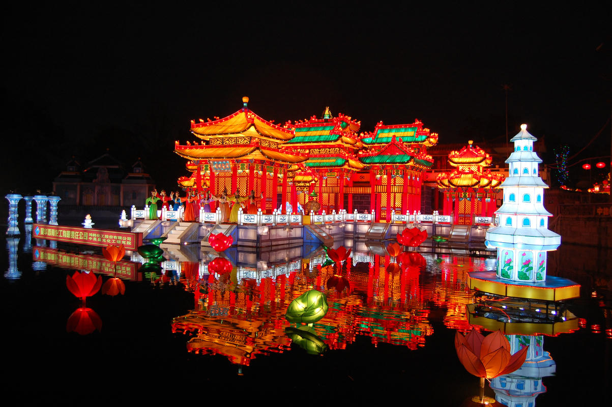 Mid Autumn Palace Lantern Night Attraction Traditional palace and pagoda lantern displays reflected on water during a Mid Autumn Festival