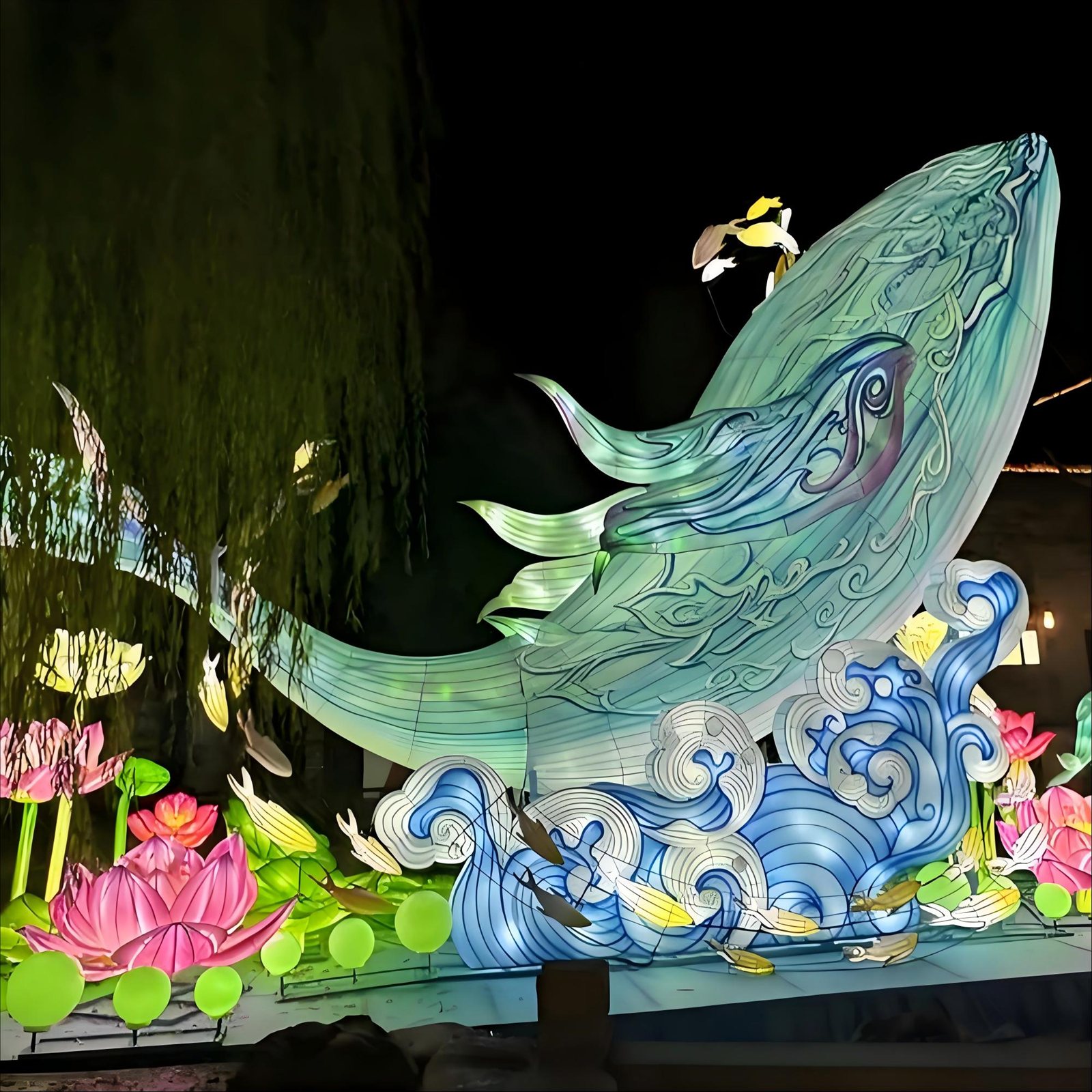 Illuminated whale lantern surrounded by wave forms, fish and flower lanterns