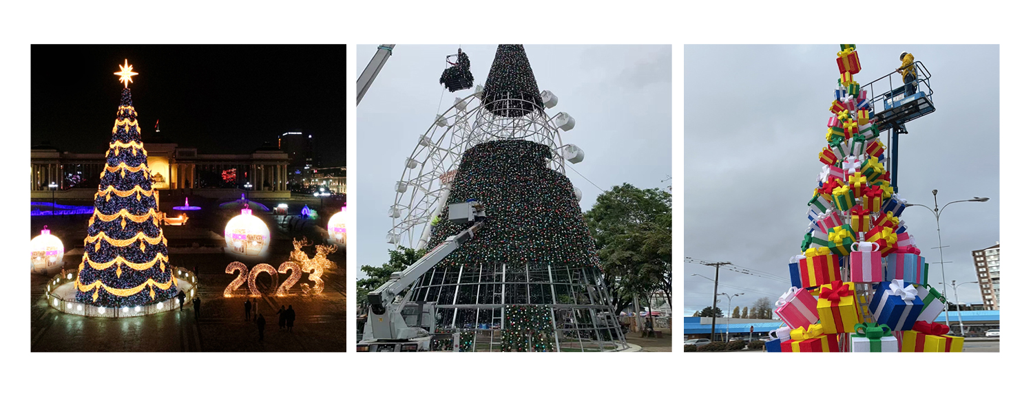 A triptych of Christmas tree displays. The first image shows a large, illuminated Christmas tree adorned with blue and yellow lights, surrounded by festive decorations and the year "2023" in lights at night. The second image depicts a tall Christmas tree under construction with a crane and Ferris wheel in the background, covered in colorful lights. The third image features a unique Christmas tree made of stacked, colorful gift boxes, with a worker on a lift assembling it during the daytime.